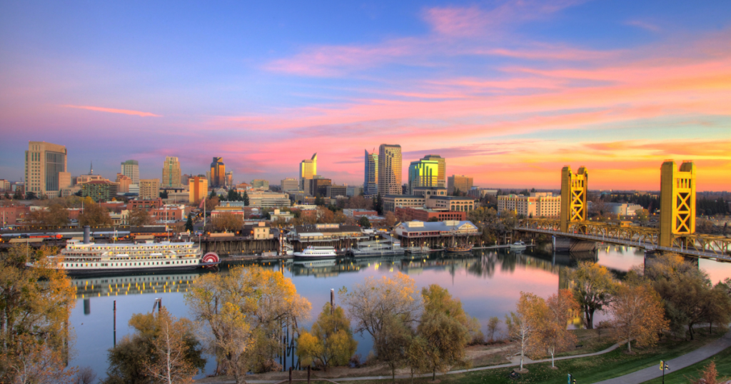 City skyline of Sacramento with river in foreground, located near East Sacramento, home to Sutter Park.